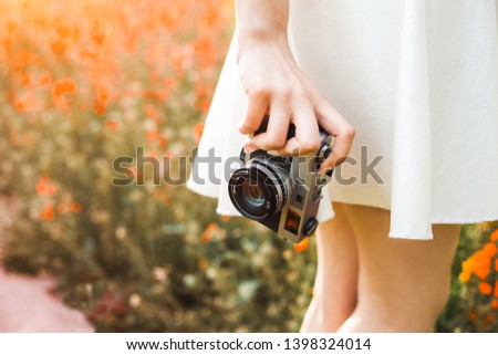 close-up photo, hand holds analog film camera on the background of a colorized flowering field the concept of creativity and self-expression