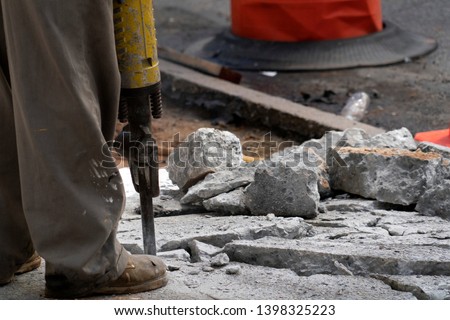Man working with jackhammer on the road detail