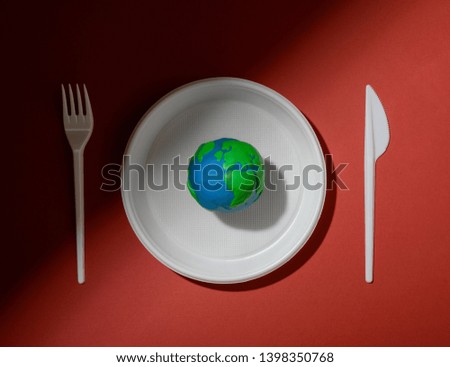 Serving table with Earth planet, plastic plate, fork and knife. Ecology Concept for Earth Hour, Earth Day, Ocean Day and other ECO dates.