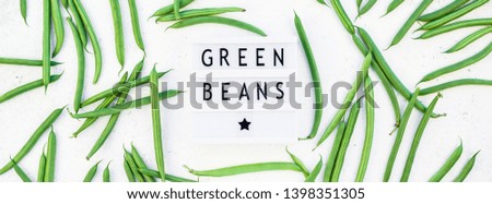 Creative scandinavian style flat lay top view of fresh green beans and text in lightbox on white concrete table background copy space. Minimal house cooking concept template for blog or recipe book