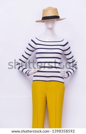 Female in striped sweater with yellow pants ,hat on mannequin