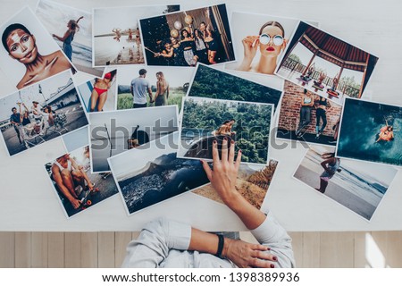 Top view of a photographer selecting best photos from several photo shoot. Female photographer working in studio looking at the prints lying on desk. Royalty-Free Stock Photo #1398389936