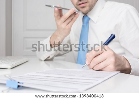 Man working in the office, speak by phone, documents on his desk, close up