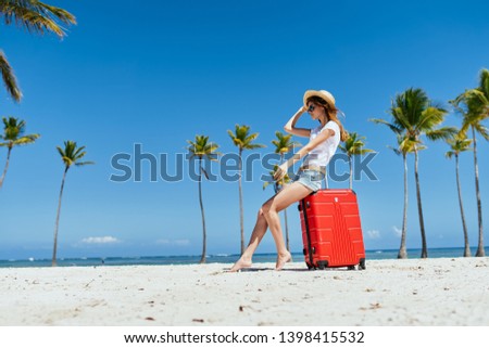 Woman sitting on a suitcase beach trip vacation tropics sun sand relax