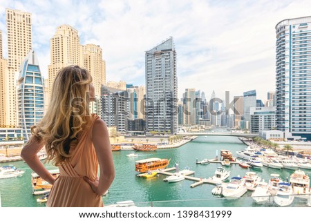 Woman in Dubai Marina, United Arab Emirates. Attractive lady wearing a long dress admiring Marina harbor daylight view Royalty-Free Stock Photo #1398431999