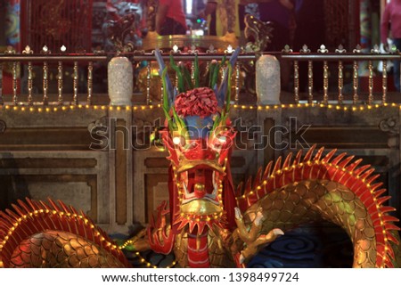 A closeup photograph of a dragon statue at the base of a temple with a focus on its nose. The word on the dragon's forehead says 王 which means 'King'.