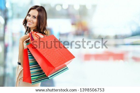 Shopping woman. Happy girl holding grocery bags, at mall background. Copyspace for some slogan, advertising or text. Brunette model - consumerism, sales and shopaholic concept picture. 