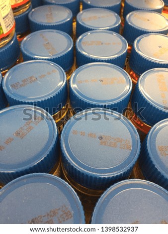 Stocked shelf of bottles with blue lids showing expiration date