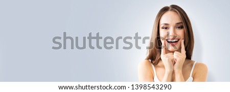 Happy excited woman showing toothy smile. Portrait of optimistic girl. Grey color background with Copy Space area, for some advertising text or slogan. Optimism or Dental Health Care concept picture.