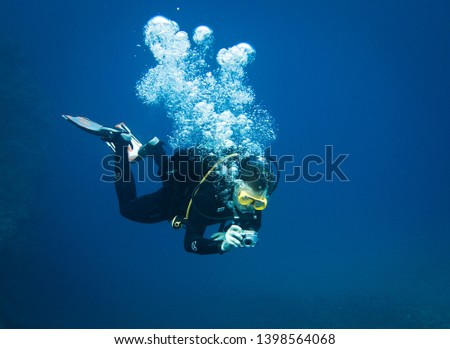 Scuba diver taking underwater photo in deep blue water