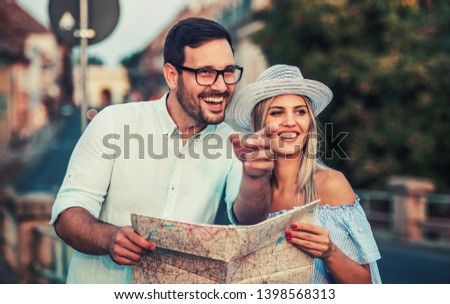 Beautiful couple on vacation using the city map and exploring the locations. Concept of tourism