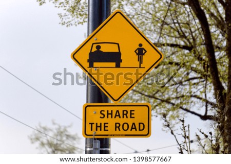 Closeup of a Share the Road sign with car and bicycle pictograms, on a lamp post
