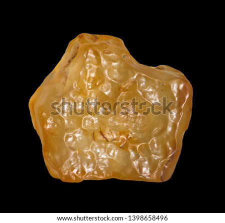 Yellow tektite specimen isolated on black background close-up. Libyan desert glass 