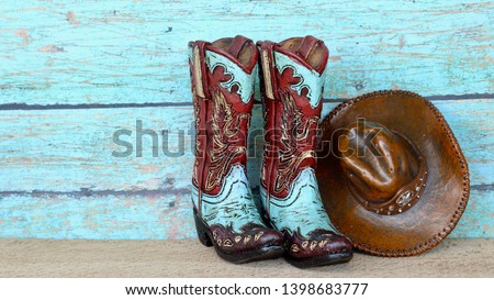pair of colorful blue and red cowboy boots and hat standing on natural wood with a blue wooden background