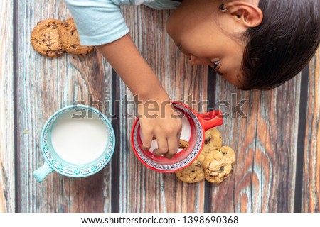 Cute little girl eating cookies with milk