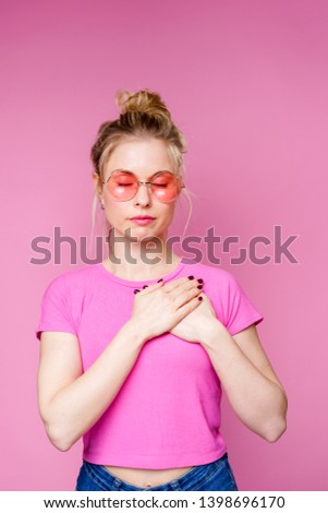 Photo of blonde in pink t-shirt holding hands over her heart
