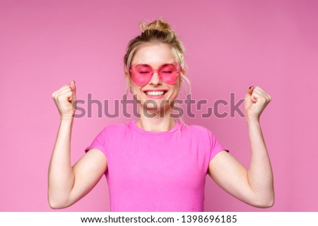 Photo of cheerful blonde in pink T-shirt with raised hands