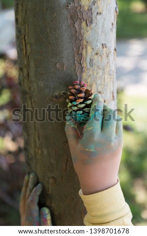 the child paint her hands and hug the tree with finger paint.