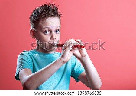 a boy in a light t-shirt playing on a pipe on a bright colored background