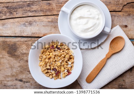 Healthy breakfast background. Muesli with yoghurt in bowl on wooden background.