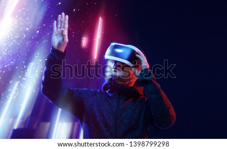 Model young man with beard in glasses of virtual reality. Augmented reality, science, future technology, people concept. VR. Futuristic 3d glasses with virtual projection. Neon light.