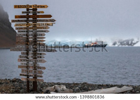 Pointer to different countries of the world whith a small pasanger vessel in the backround in Antarctica