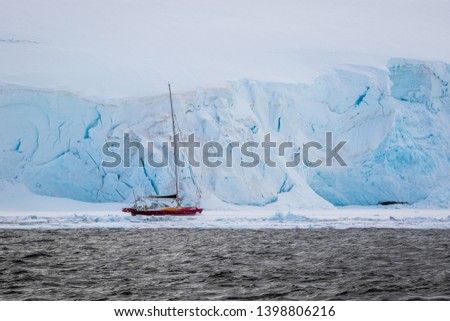 Sailing yacht is staying on anchorage in Antarctica with glacier in the background