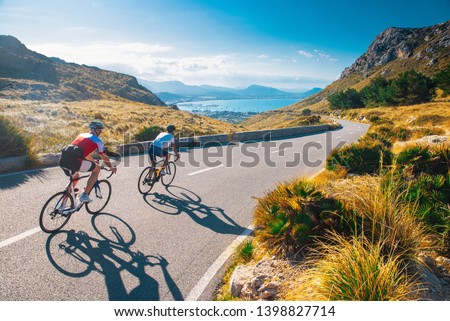 Road cycling photo. Two triathlete train in beautiful nature. Sea and mountains in background. Alcudia, Mallorca, Spain Royalty-Free Stock Photo #1398827714