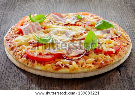 Pizza with bacon and tomato on wooden cutting board