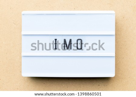 White lightbox with word IMO (Abbreviation of in my opinion) on wood background