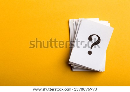 Pile of stacked question marks printed on sheets of white paper or signs arranged to the side on a yellow background with copy space in a conceptual image.