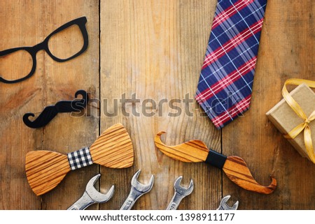 Father's day concept. Hipster glasses, gift box, tie and funny moustache over wooden background. top view, flat lay