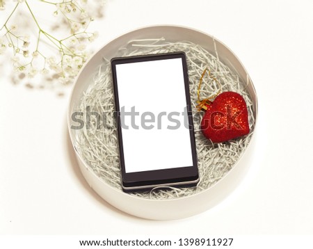 love concept. the photo of smartphone with white blanknscreen in the round container. and heart mobile.l. on the white back ground and flower decoration.  the father's day concept