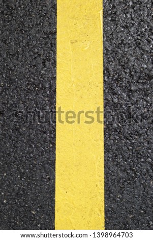 Yellow line painted on the asphalt.