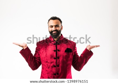 Indian man presenting while wearing traditional sherwani. standing isolated over white background