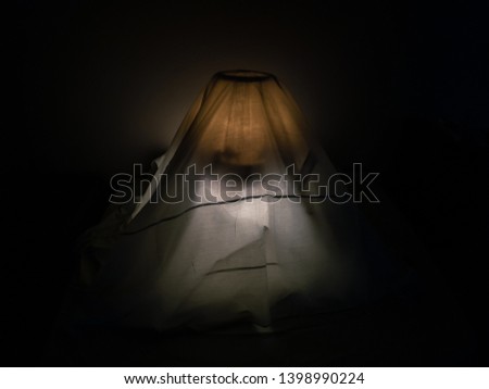 Lamp covered with white blanket in the dark environment