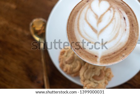 Hot latte in white cup on wooden background. To make one good cappuccino, quality grain & beautiful latte art foam is a key. This picture can be used as background. Copy space given. Chillout concept.