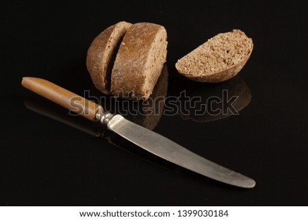 Table knife and rye bread on a black mirror background