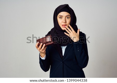  surprised hijab woman holding a case for glasses on a gray background                             