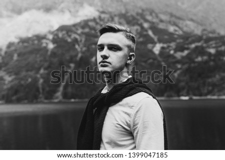 Black and white photo of a young man in the mountains.