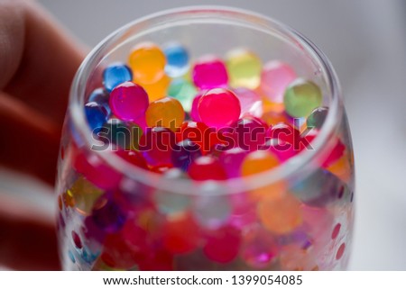 In the glass staan are round colored candies.