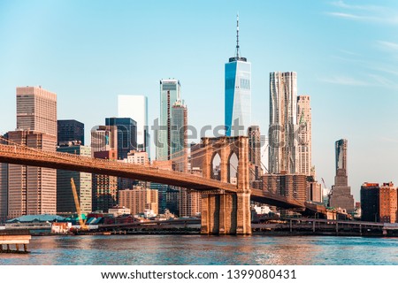 Amazing panorama view of New York City skyline and Brooklyn bridge with skyscrapers and East River flowing during daytime in United States of America
