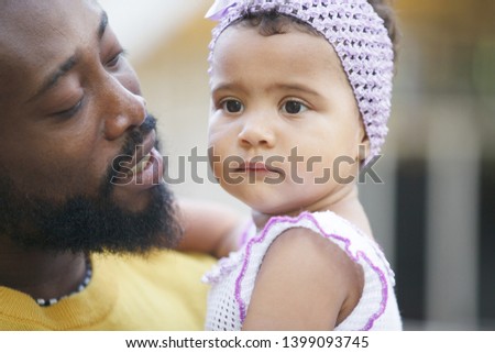 African father holds his little daughter in his arms, hugs and kisses.