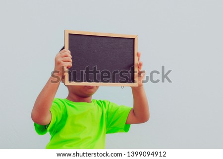 Little Asian boy holding empty chalkboard 