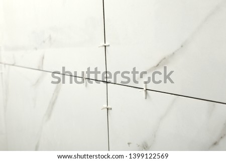 Closeup view of ceramic tiles with plastic crosses in joints on wall. Building and renovation works