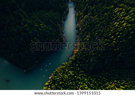 Lake ina pine tree forest with small boats seen from a drone 