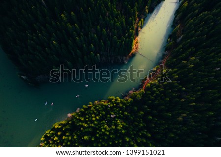 Lake ina pine tree forest with small boats seen from a drone 