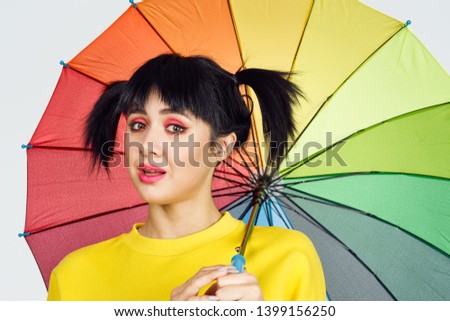  girl with ponytails with bright makeup holding a colored umbrella portrait                             
