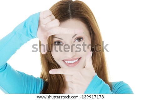 Smiling woman wearing blue blouse is showing frame by hands. Happy girl with face in frame of palms. Isolated on white background.
