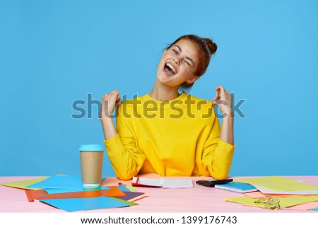 business finance emotions woman yellow sweater cup of coffee folders documents pink table                           